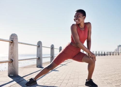 Woman in workout clothes stretching near the beach