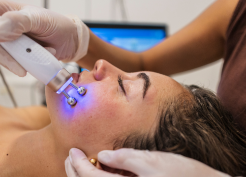 A professional esthetician using a high-frequency facial wand on a client, demonstrating the advanced techniques used during professional facials to deliver deep skin results.
